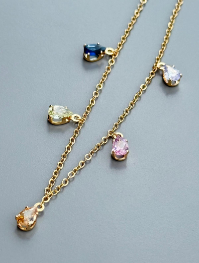 Apzeltīta ķēdīte ap kāju ar krāsainiem kristāliem